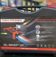 A high-power multi-function jump starter and tire inflator in a black hard carrying case, shown with promotional text overlays at the top. The case features red accents and printed product details, photographed in a real-world setting with a blurred background.